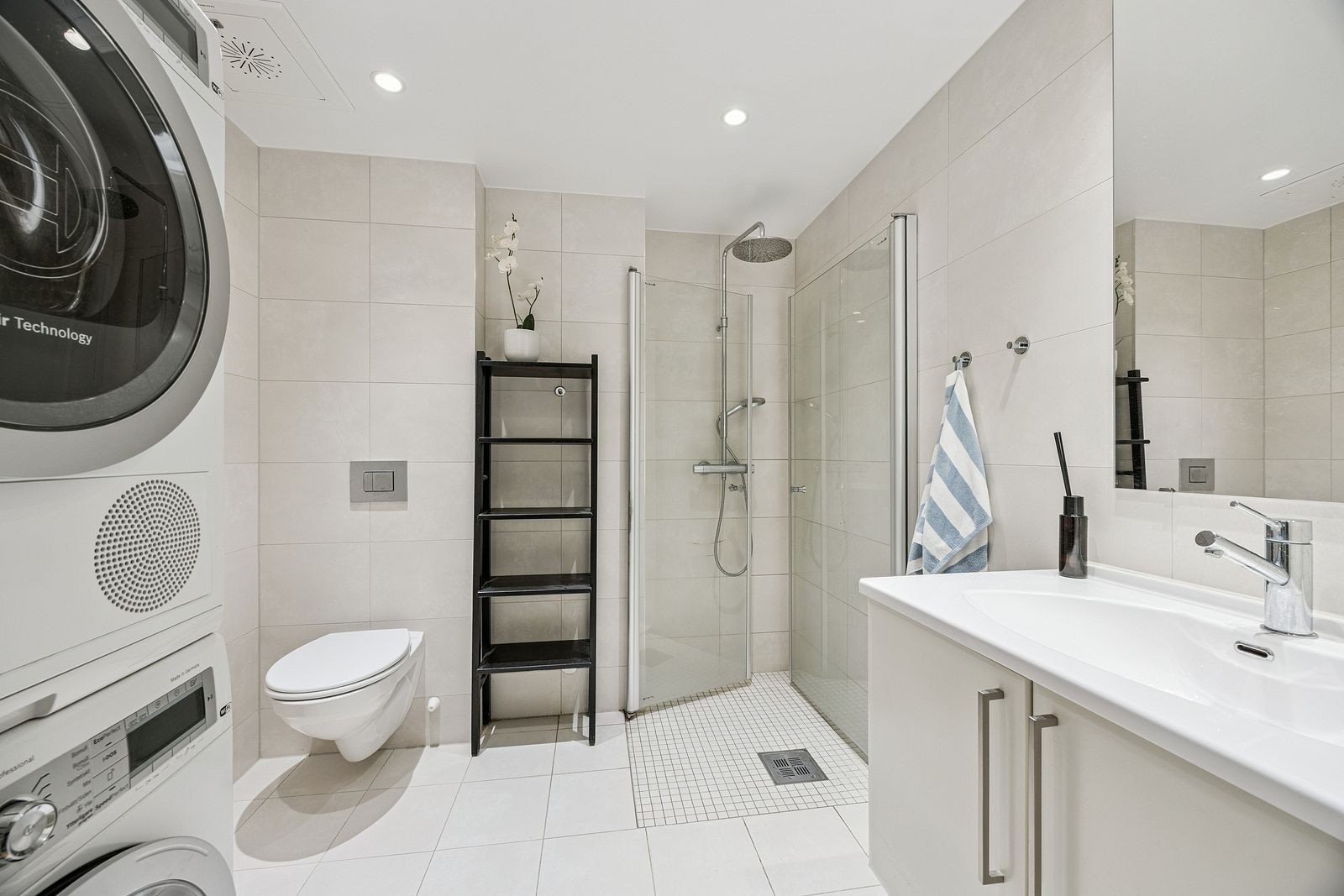 Pent bad med vaskemaskin og tørketrommel. Innfellbare dusjdører i glass og varme i gulv. Galleribilde