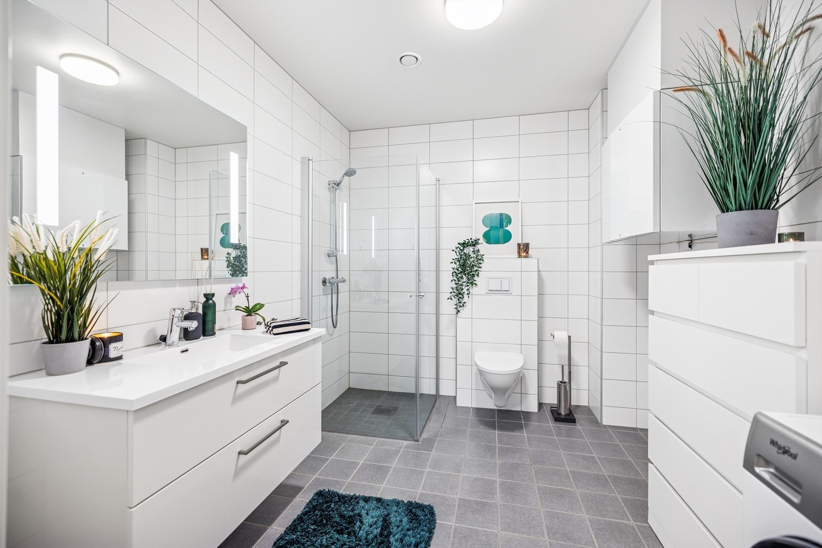 Badet er utstyrt med vegghengt toalett, dusjhjørne og opplegg for vaskemaskin. Galleribilde