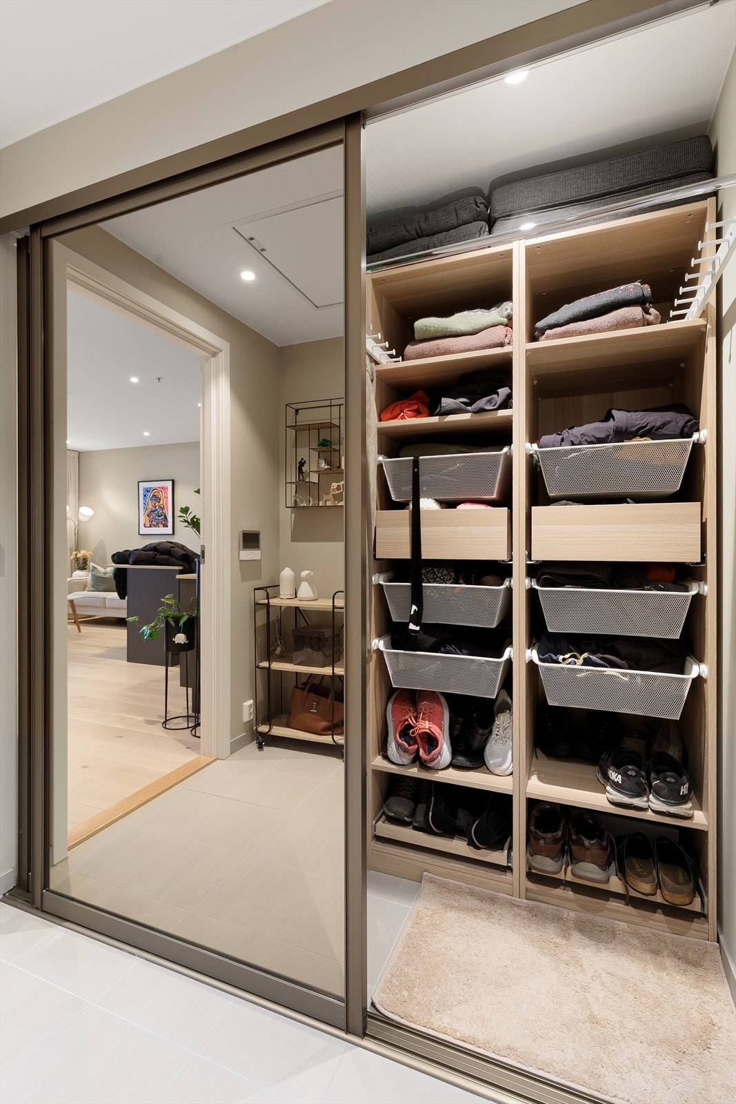 Romslig hall med flis på gulv og gode lagringsmuligheter i bod bak skyvedører med speilfronter Galleribilde