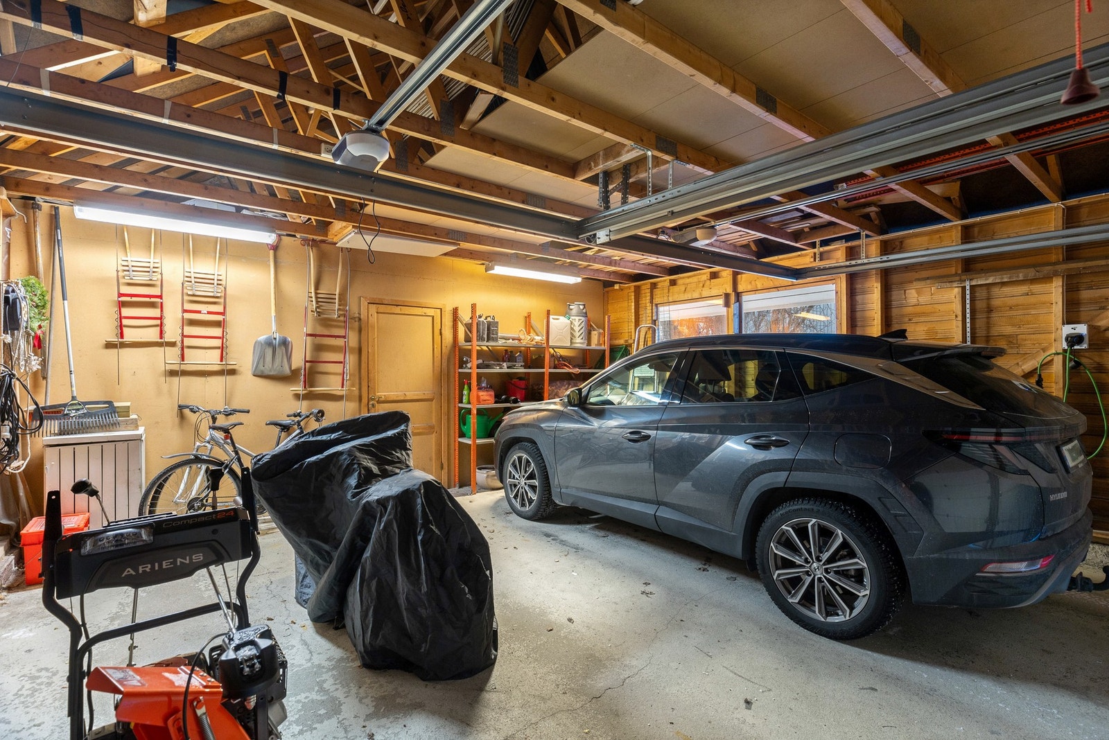 Fra vaskerommet går du tørrskodd inn i boligens flotte dobbelt garasje. Garasjen er romslig og har en redskapsbod i bakkant, to leddporter med portåpner. Portåpner fra ca. 2016. Galleribilde