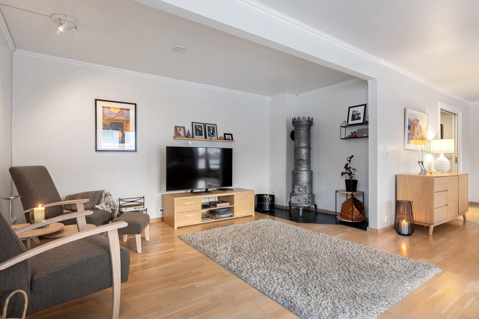 Videre inn i stuen finner vi hjemmets TV-krok. En flott restaurert antikk vedovn som ble montert i 2003. Pipen ble sist feiet i 2025. Galleribilde