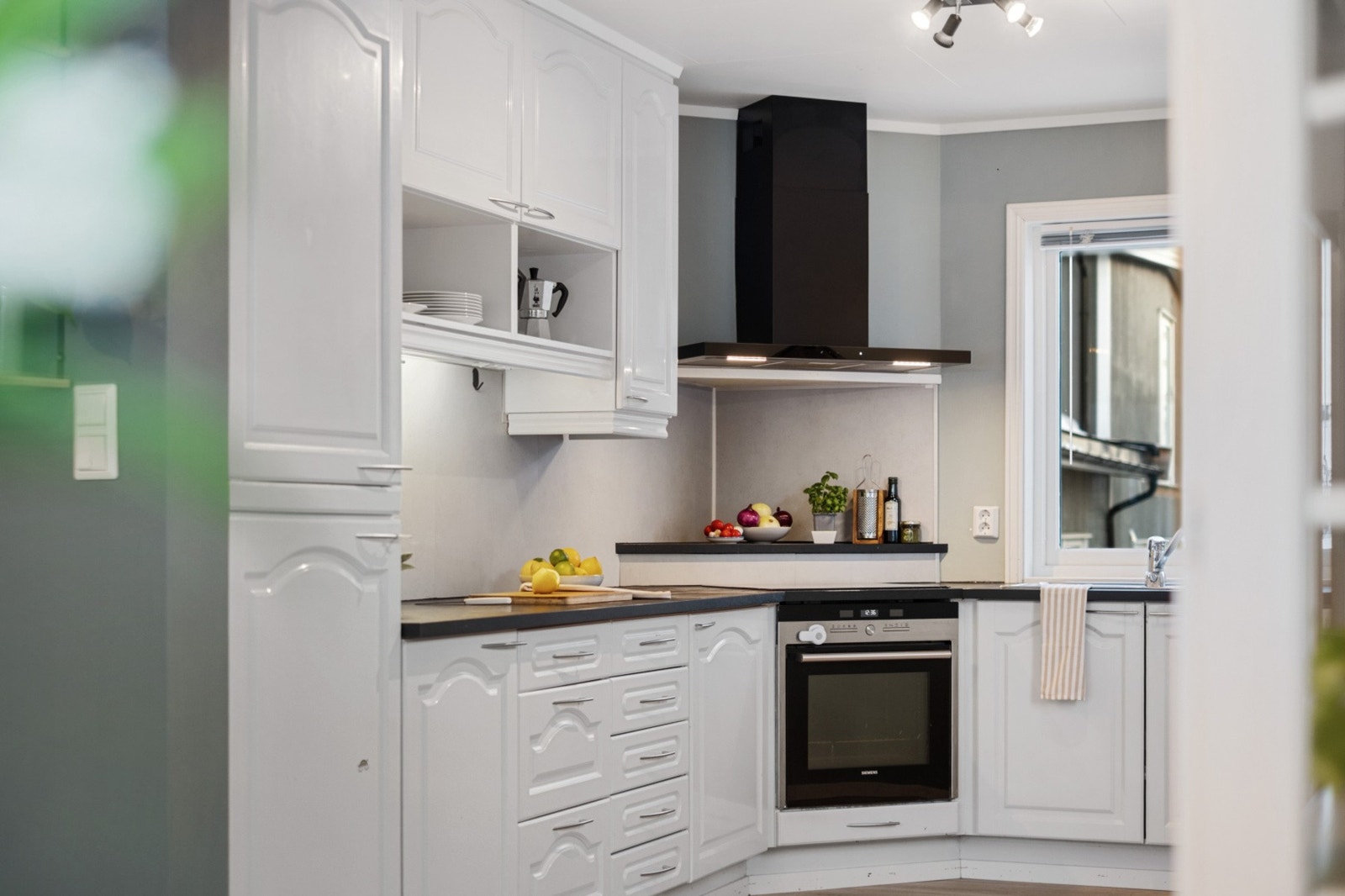 Videre består kjøkkenet av laminat benkeplate, nedfelt oppvaskkum med ett-greps kjøkkenarmatur og laminat plate mellom benk og overskap. Galleribilde