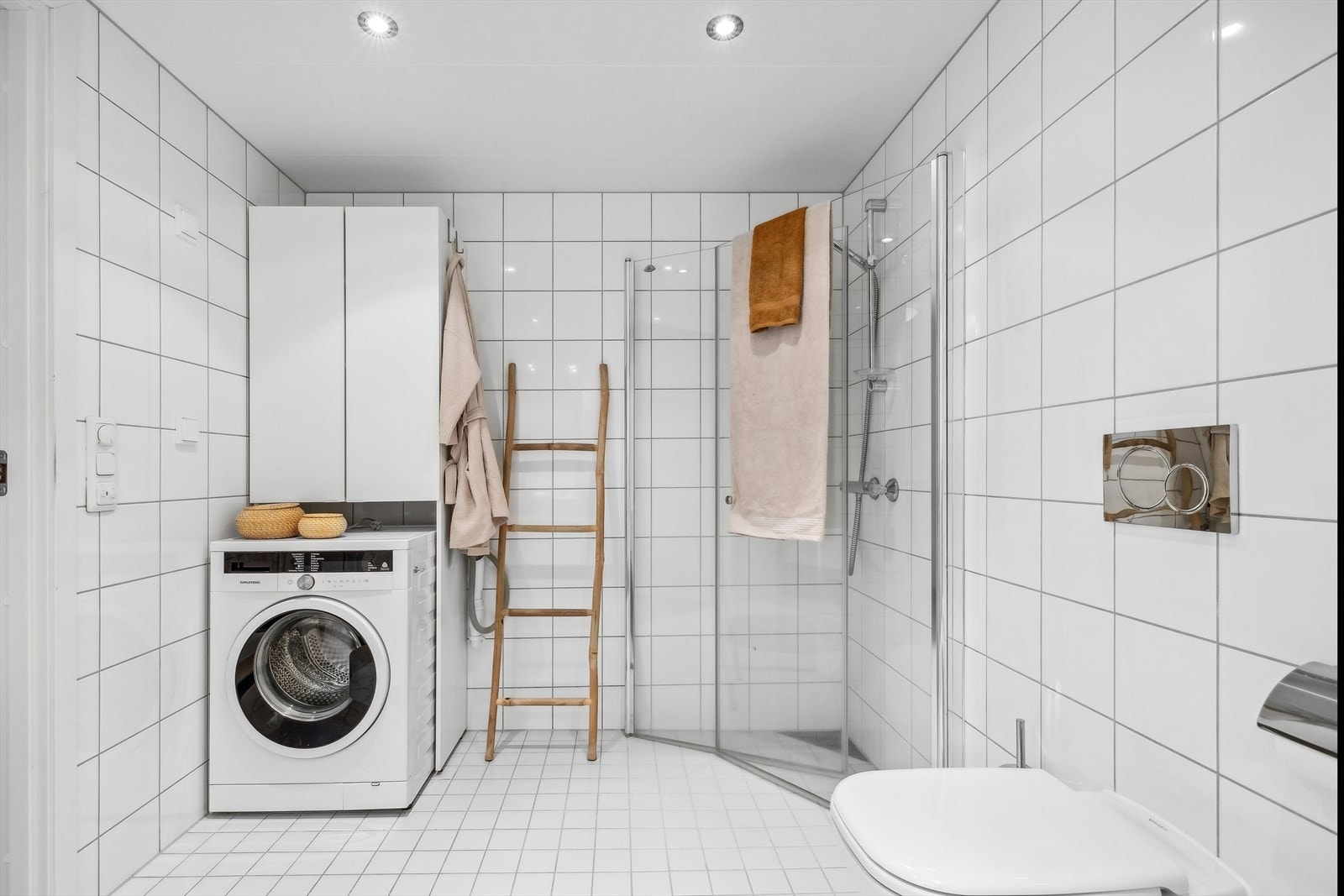 Bad har dusjvegger/hjørne, veggmontert toalett og bidè, og det er opplegg for vaskemaskin. Galleribilde