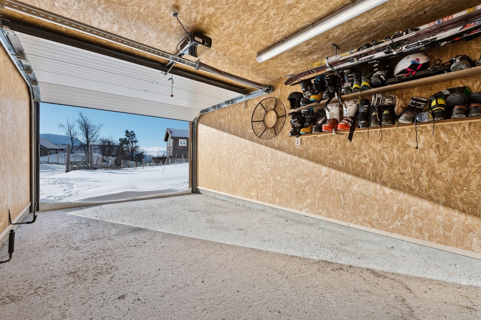 Det er parkering i en garasje med lagringsplass og fjernstyrt portåpner. El-bil lader. Galleribilde