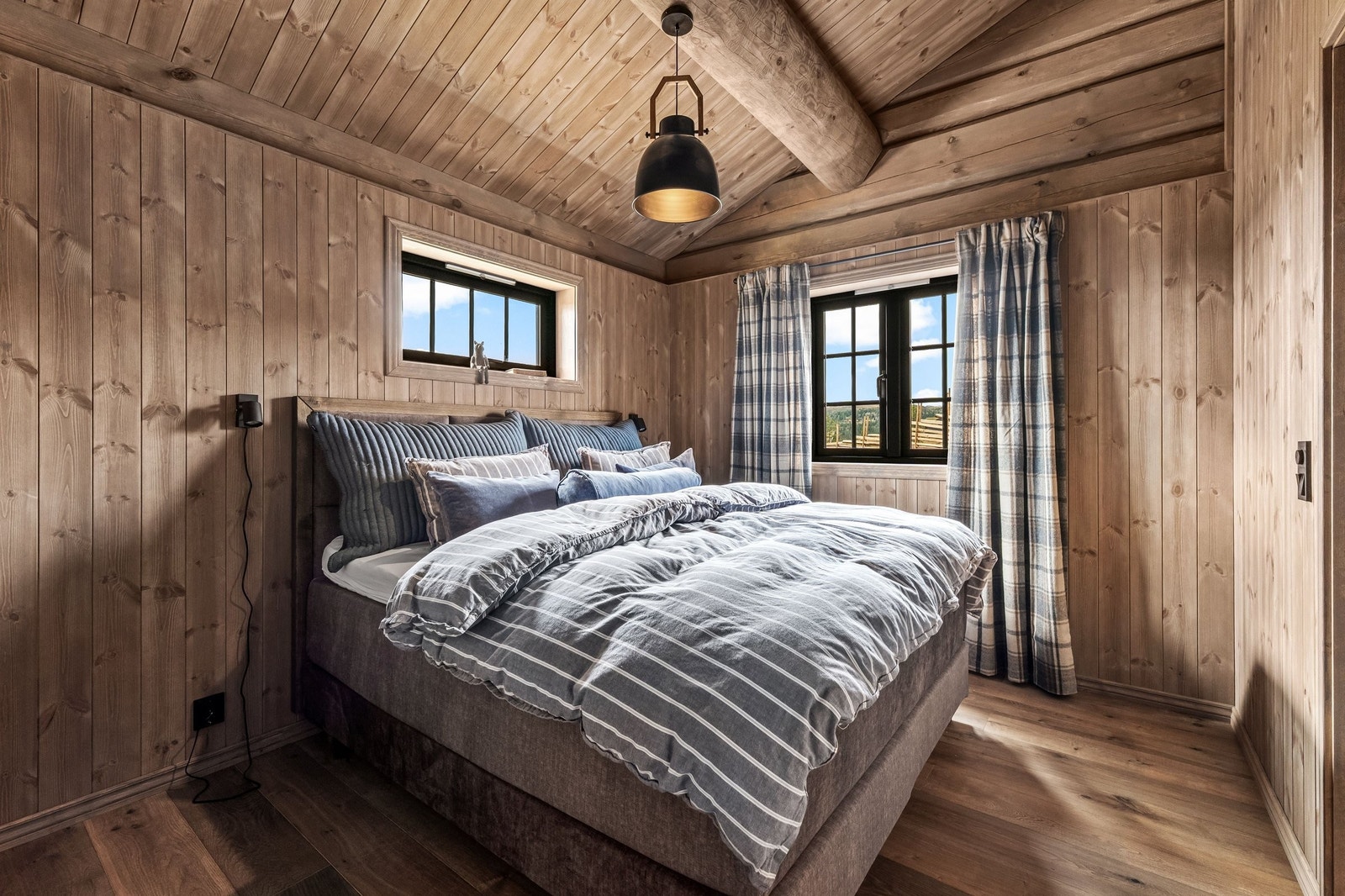 Master-soverommet i 1 etasje er romslig og har skrå himling med synlige takåser som skaper en hyggelig atmosfære Galleribilde