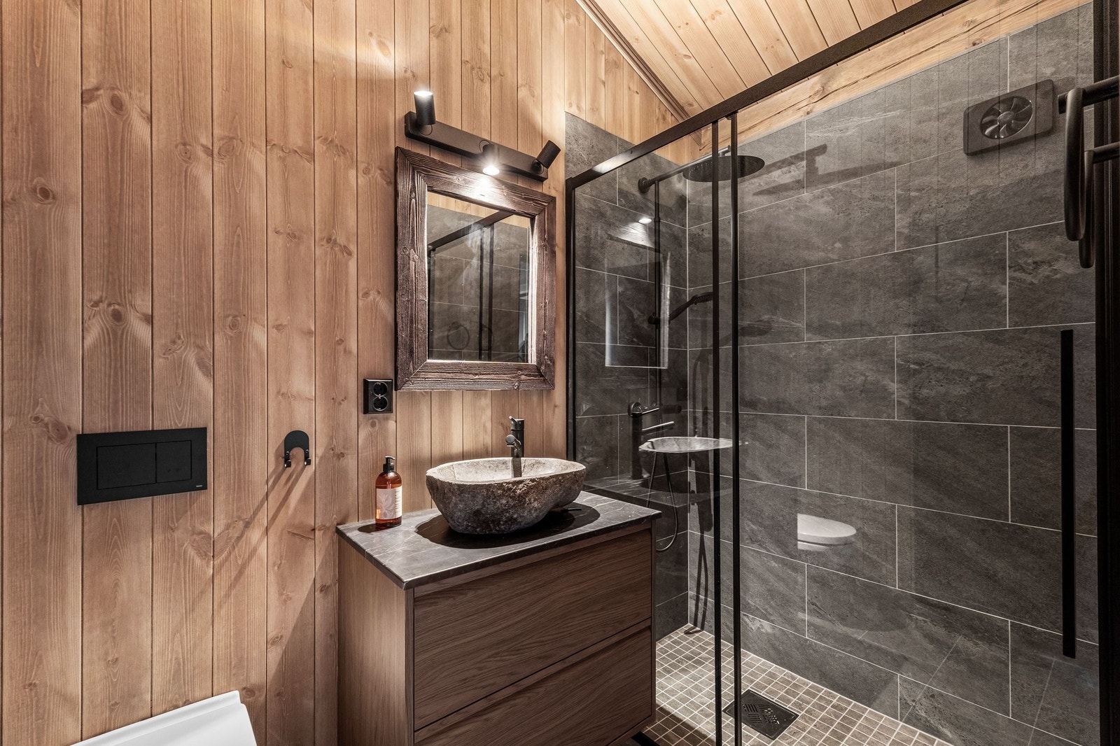 En suite bad for soverom 2 i 1 etasje har skrå himling med synlige takåser som skaper en hyggelig atmosfære. Rommet har elektrisk styrt vifte Galleribilde