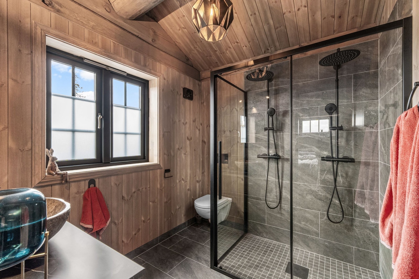 Master-bad med romslig dusjnisje med to dusjarmaturer. Rommet har elektrisk styrt vifte. Galleribilde