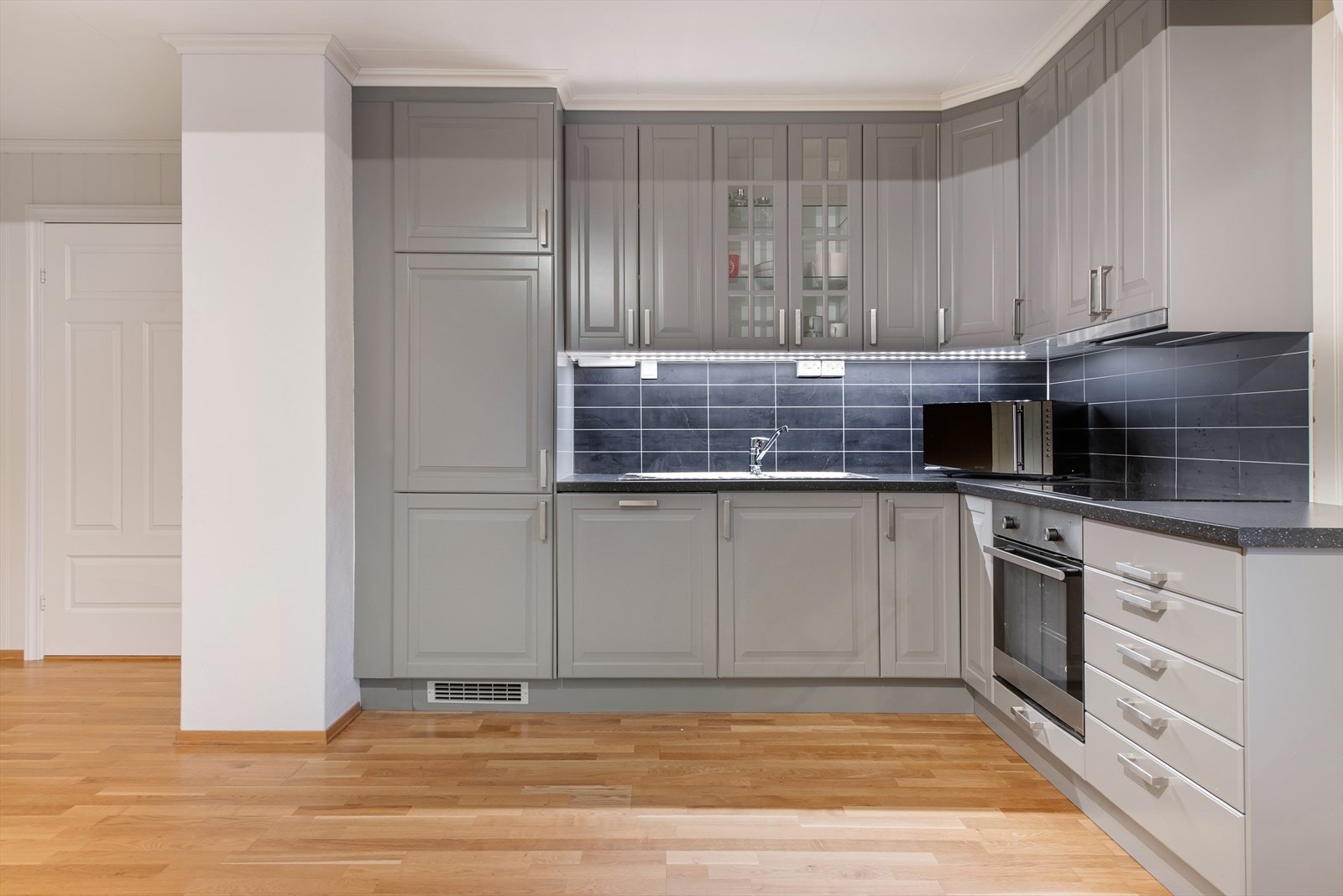 Kjøkken i 1 etg i åpen løsning med stue. Kjøkkeninnredning med malte speilfronter, laminat benkeplate, stål oppvaskkum. mekanisk ventilator og integrerte hvitevarer. Galleribilde