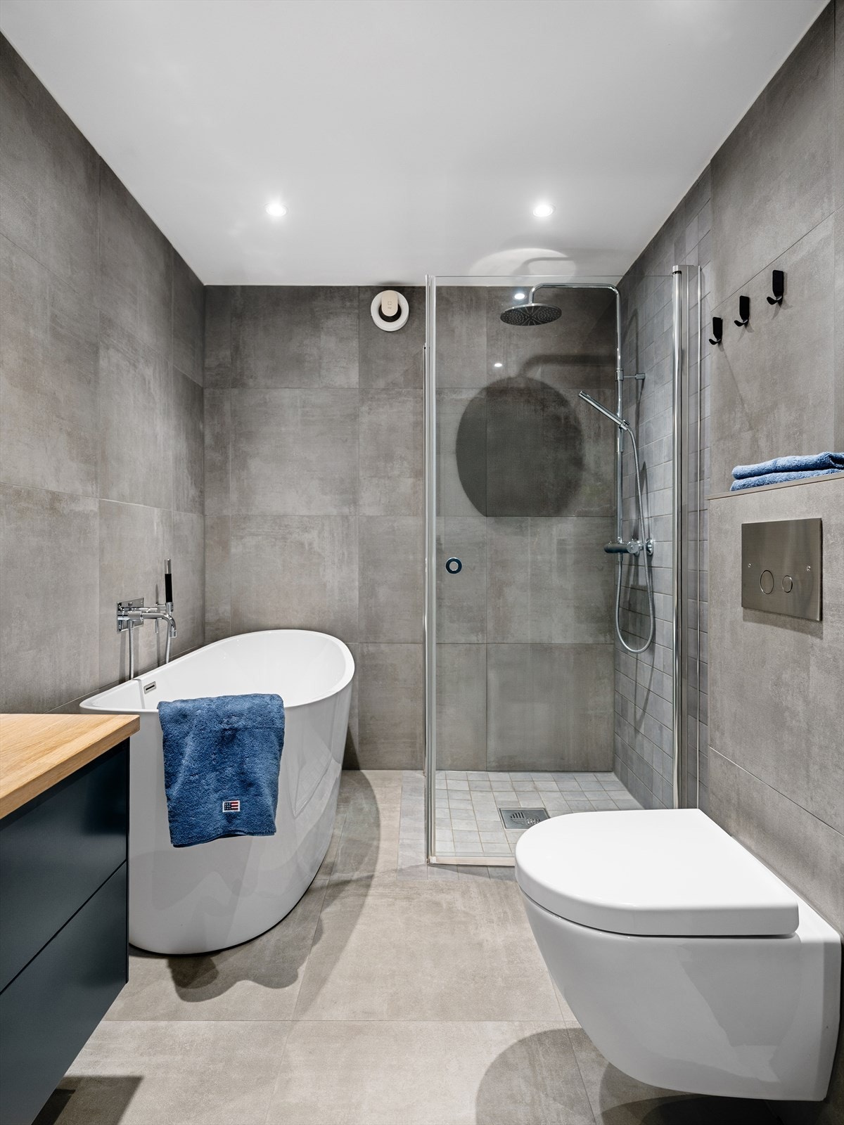 Badet har et gjennomført og tidløst uttrykk med store 60x60 cm fliser, kombinert med mindre fliser i dusjsonen som gir en fin kontrast Galleribilde