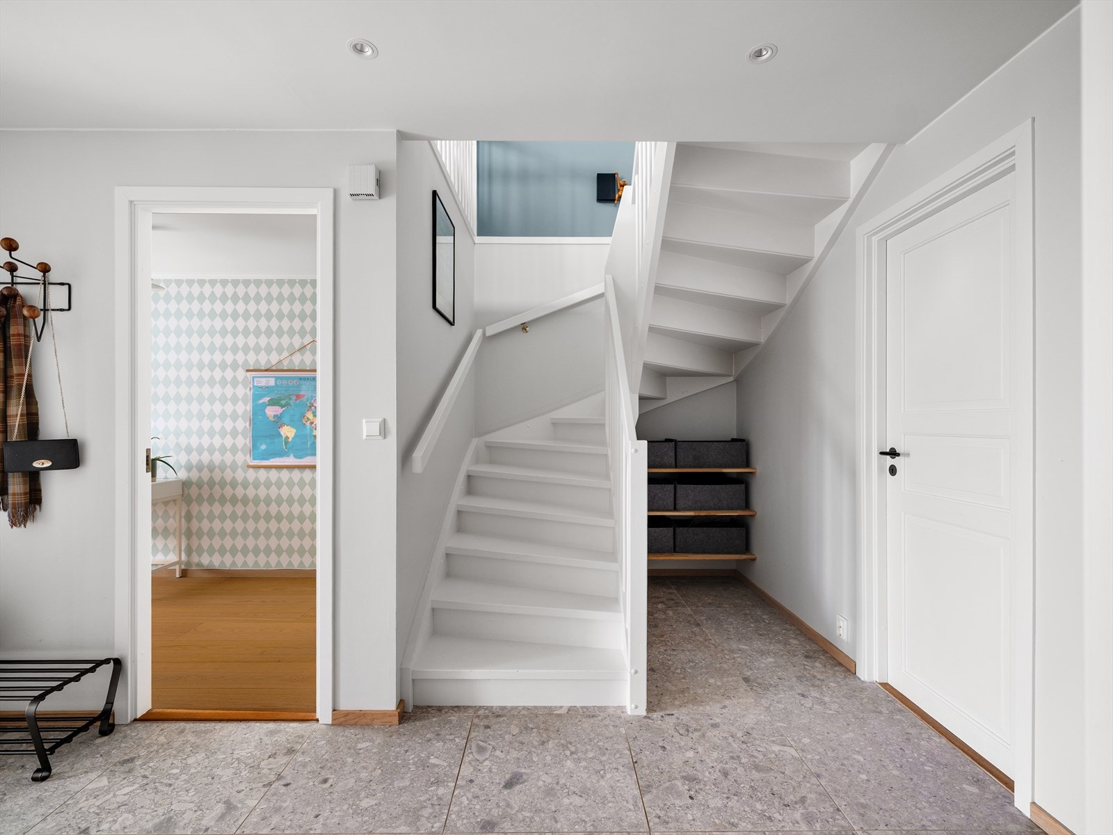 Stor hall i 1. etasje med lekre 60x60 fliser på gulv, elektriske varmekabler og downlightsbelysning. Oppbevaringsmuligheter i skyvedørsgarderobe, samt under trapp Galleribilde