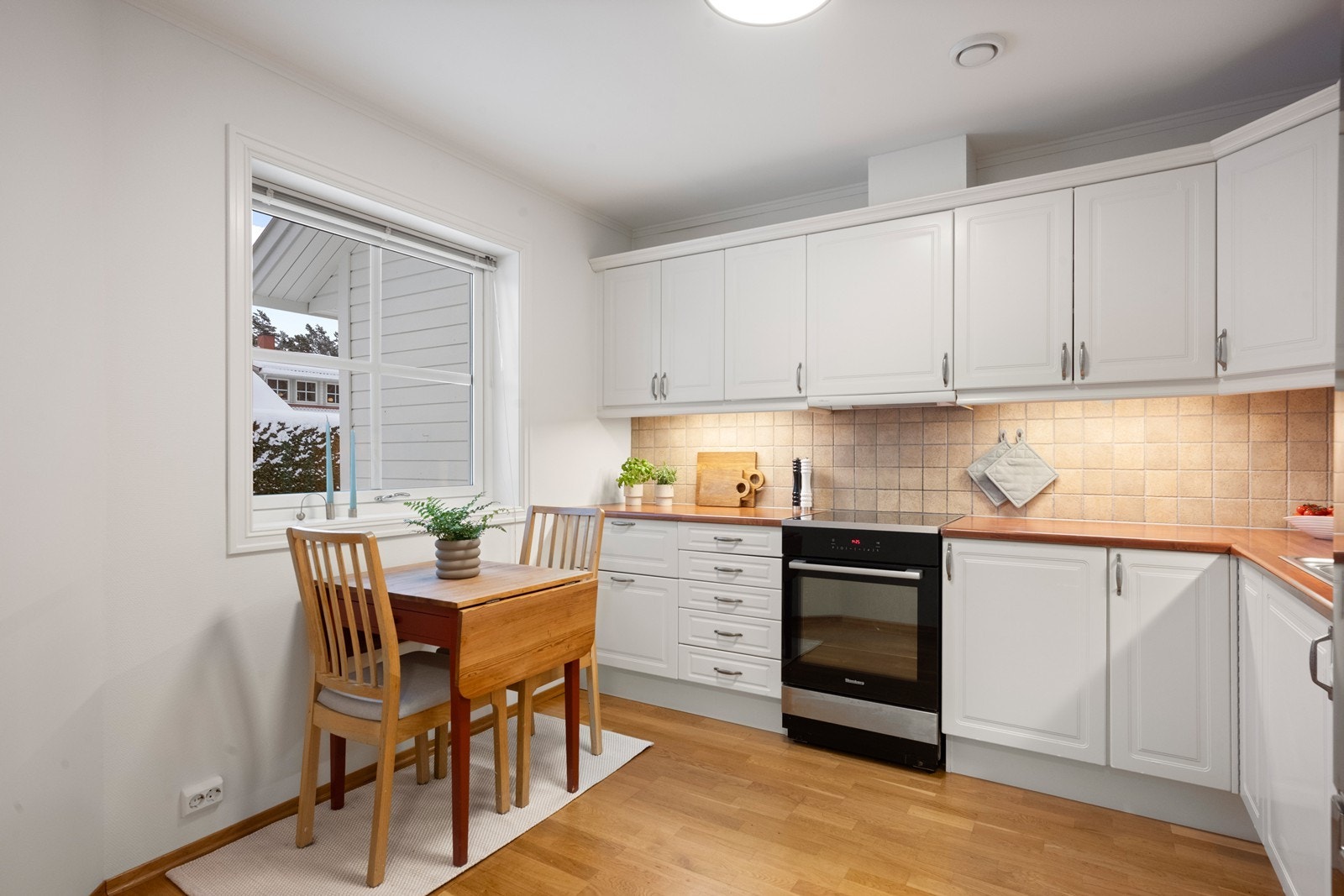 Kjøkkenet har en moderne innredning med hvite, profilerte fronter og god benkeplass. Galleribilde