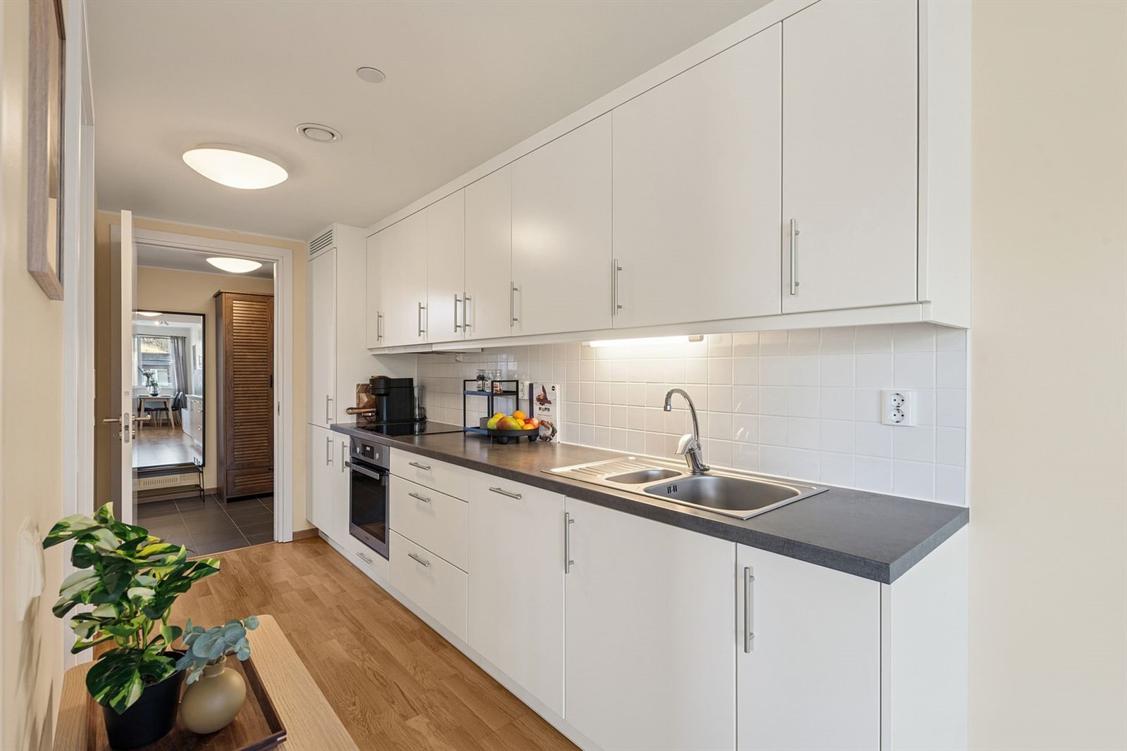 Lyst kjøkken med hvite fronter og mørk benkeplate. Galleribilde