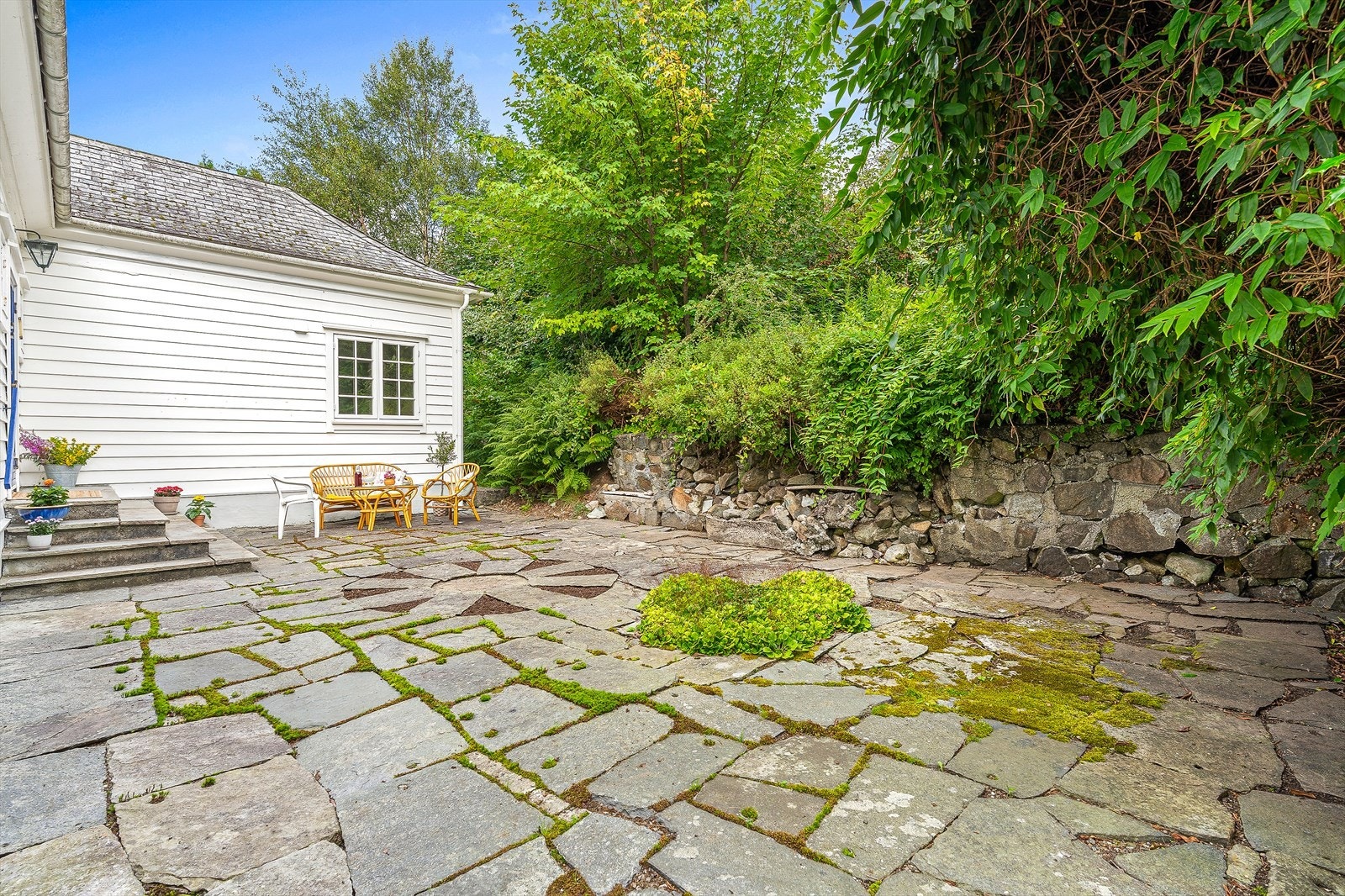 Inngangspartiet har en steinlagt gårdsplass med plass til en hyggelig sittegruppe. Galleribilde