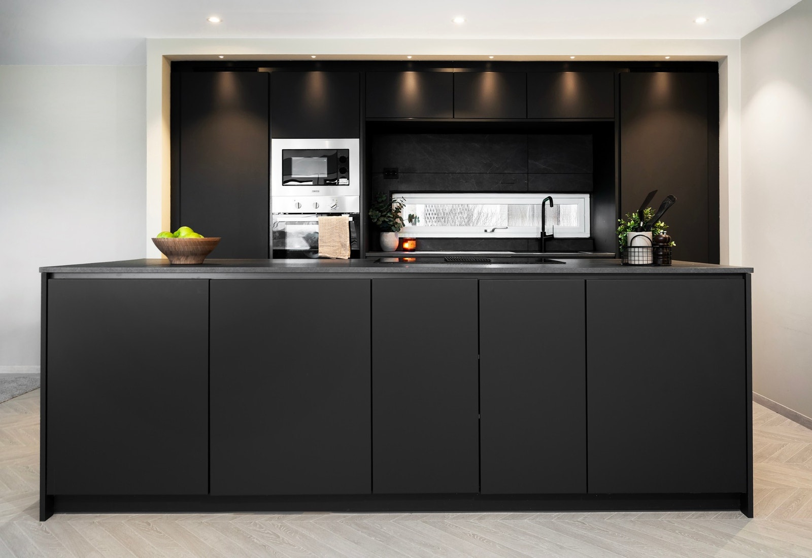 Lekkert påkostet kjøkken fra KVIK - legg merke til spotter og innforing rund innredning for et sømløst uttrykk. Galleribilde