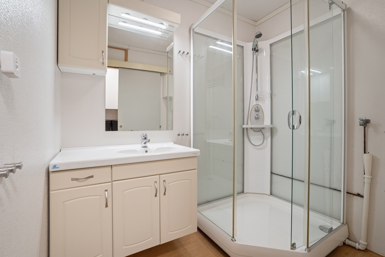 Baderommet er innredet med belegg på gulv og malt strie på vegg. Rommet er ellers utstyrt med dusjkabinett og baderomsinnredning med nedfelt servant. Galleribilde