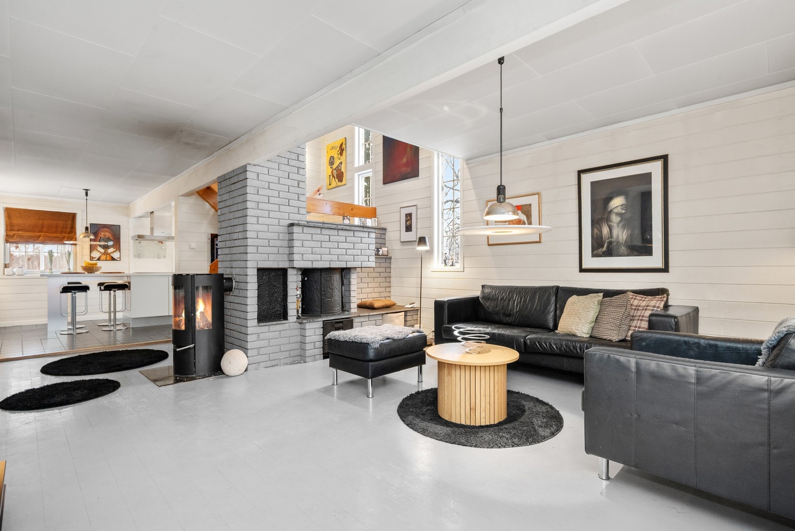 Det er åpen løsning med peis og vedovn som skiller stue og kjøkken. Galleribilde