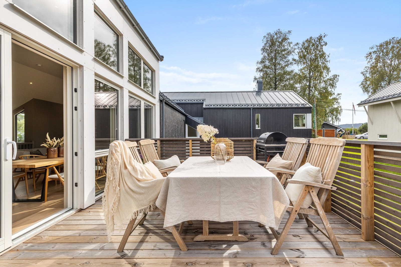 Nyt solen på den store altanen. Moderne fasade med store vindusflater. Galleribilde