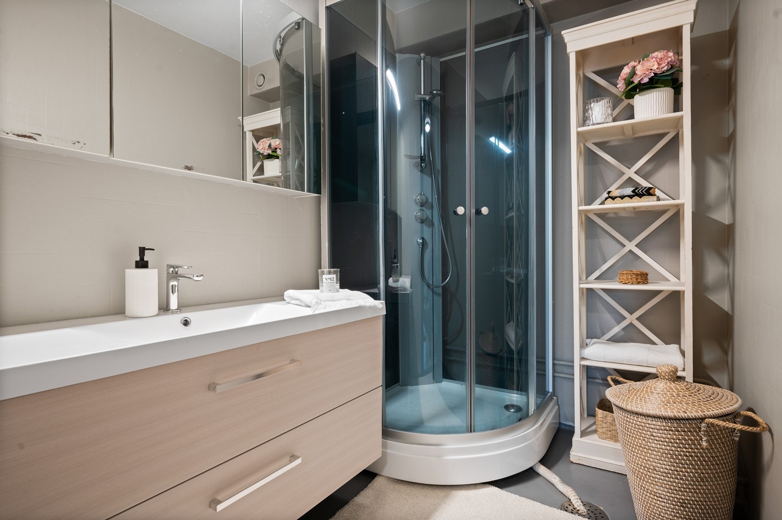 Baderommet har et praktisk dusjkabinett og en stilren servantløsning Galleribilde