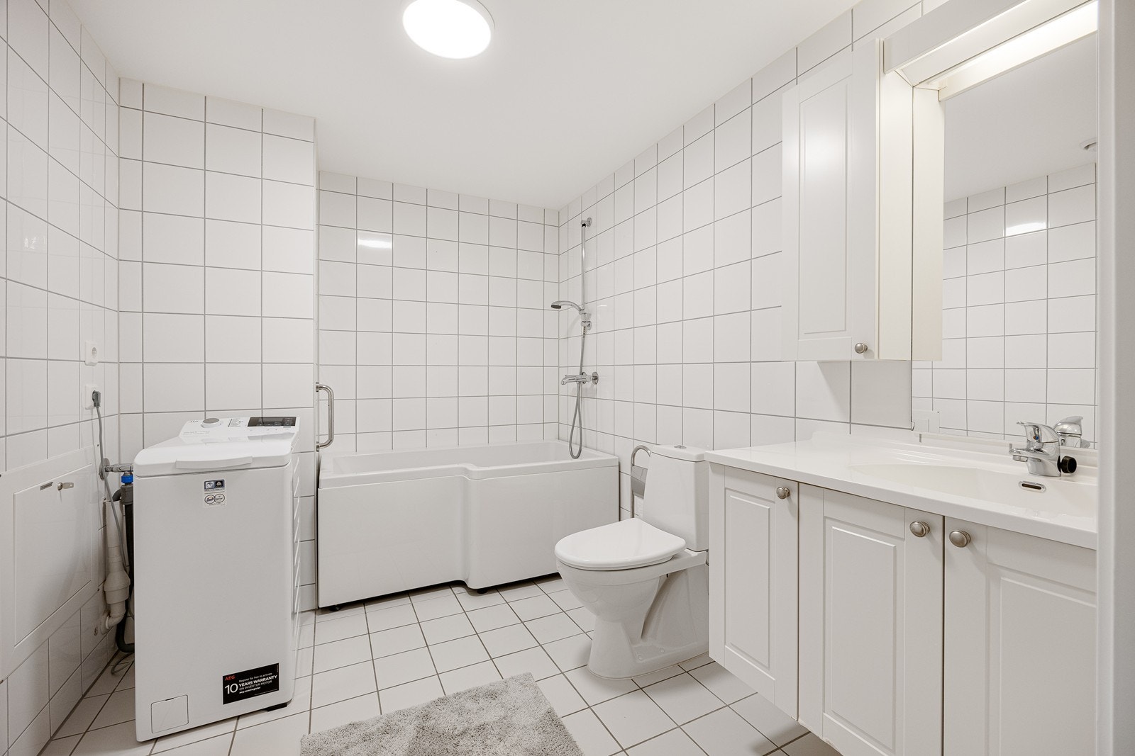 Videre har badet et toalett, opplegg for vaskemaskin og et badekar med veggmontert dusjarmatur. Galleribilde