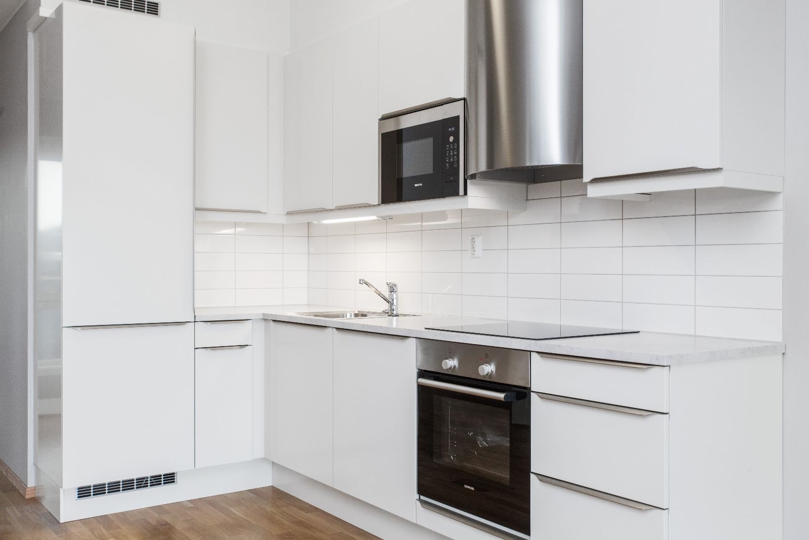 Pent kjøkken med integrerte hvitevarer og Røroshetta. Galleribilde