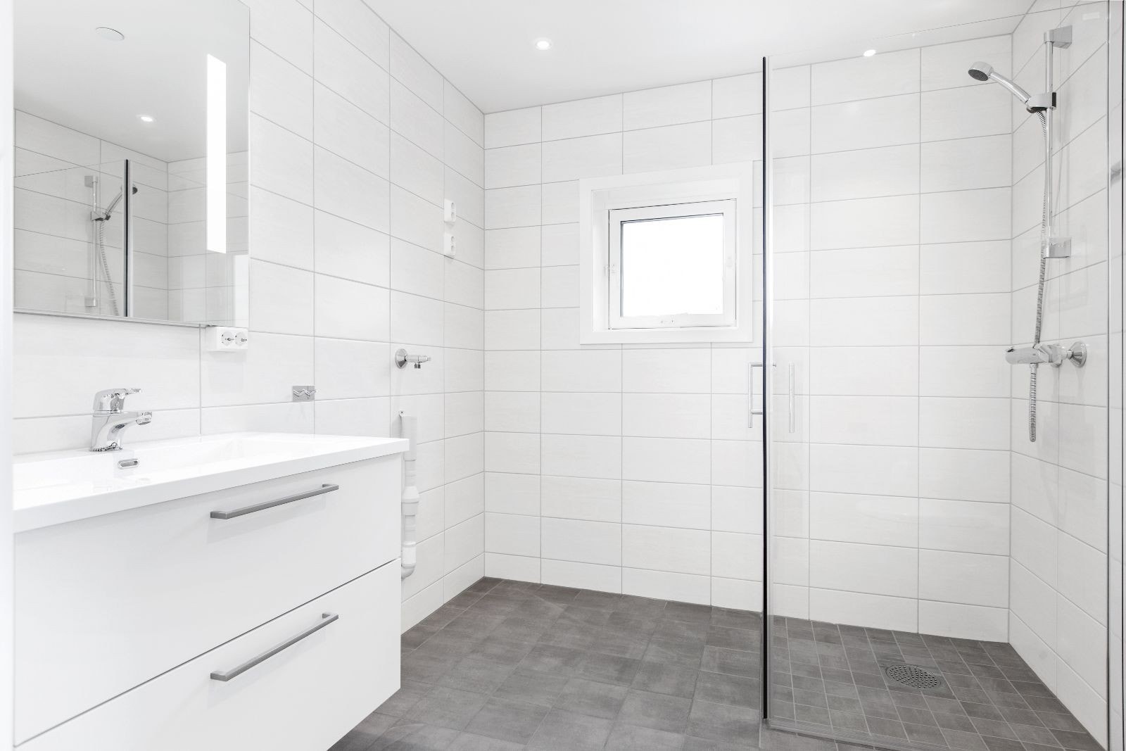 Lekkert flialgt bad med varme i gulv, innfellbare dusjvegger og opplegg til vaskemaskin. Galleribilde