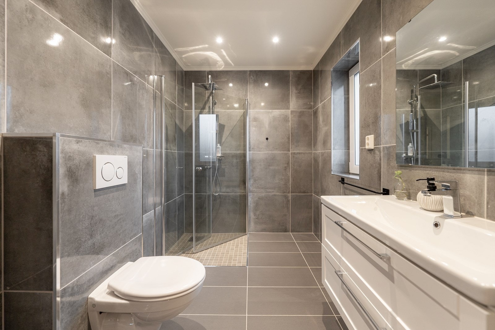 Fra soverommet kommer du til badet i 2.etasje. Badet er flislagt med varmekabler i gulv og malte slette flater i taket. Badet er innredet med nedfelt servant, veggmontert toalett og dusjhjørne med praktisk dusjdører. Galleribilde