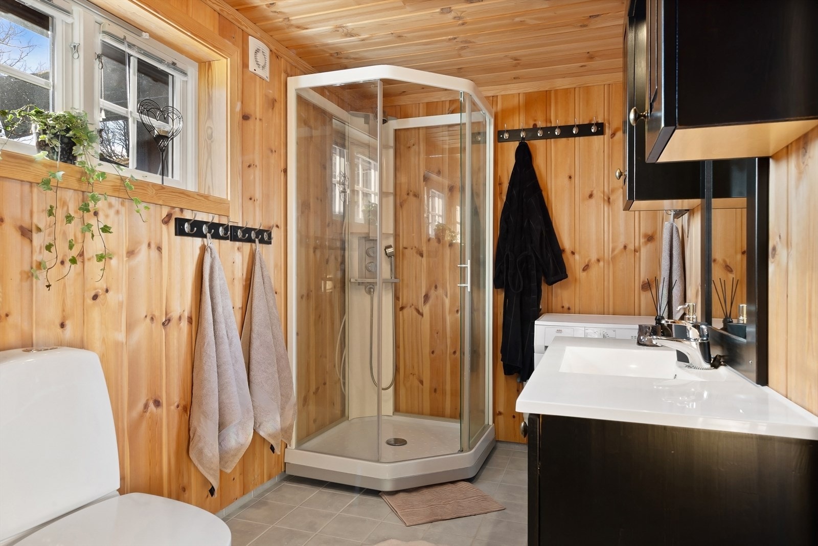 Badet inneholder servantinnredning med speil, dusjkabinett og toalett. Tilstøtende badstue. Galleribilde