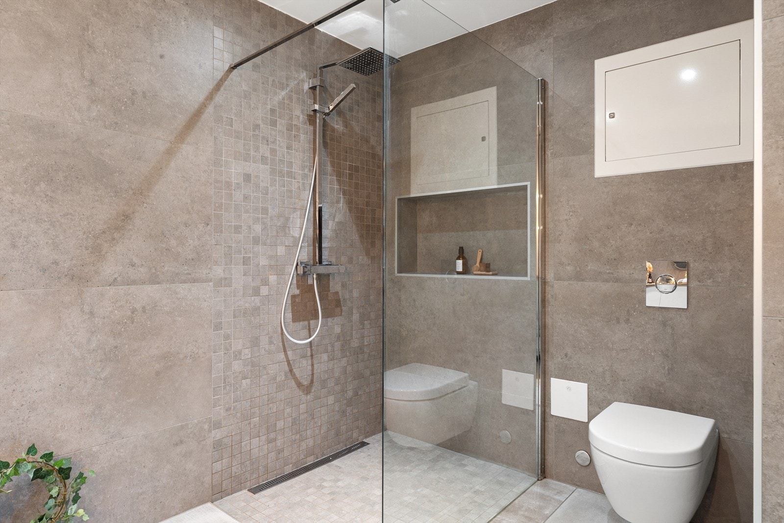 Her får du et helfliset baderom med komfortabel gulvvarme, innredet med servant i møbel, vegghengt toalett og dusj med glassvegg. Galleribilde