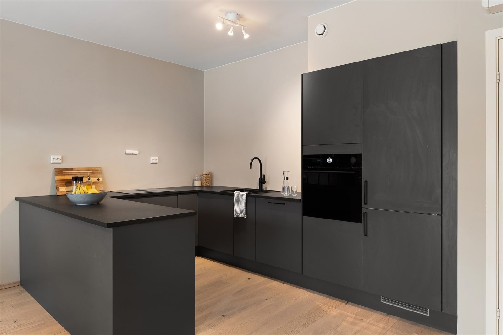 Lekkert kjøkken med integrerte hvitevarer som kjøl/fryseskap, oppvaskmaskin, induksjonstopp, stekeovn, vannstoppsystem og komfyrvakt Galleribilde