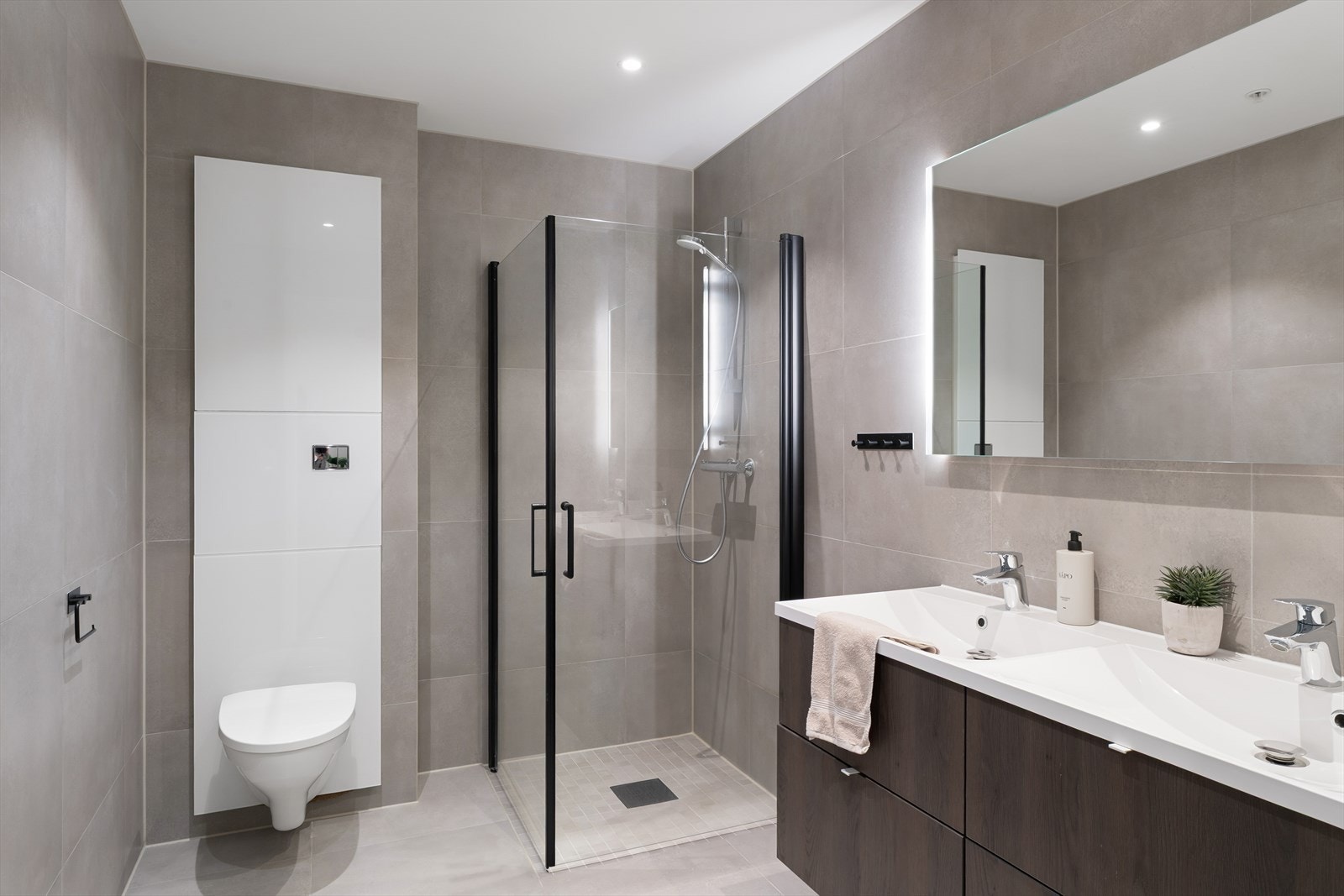 Bad nr. 2: Start og avslutt dagen kun et par skritt fra sengen! Et innbydende, helfliset bad med dobbel servant, vegghengt toalett og praktiske dusjdører Galleribilde