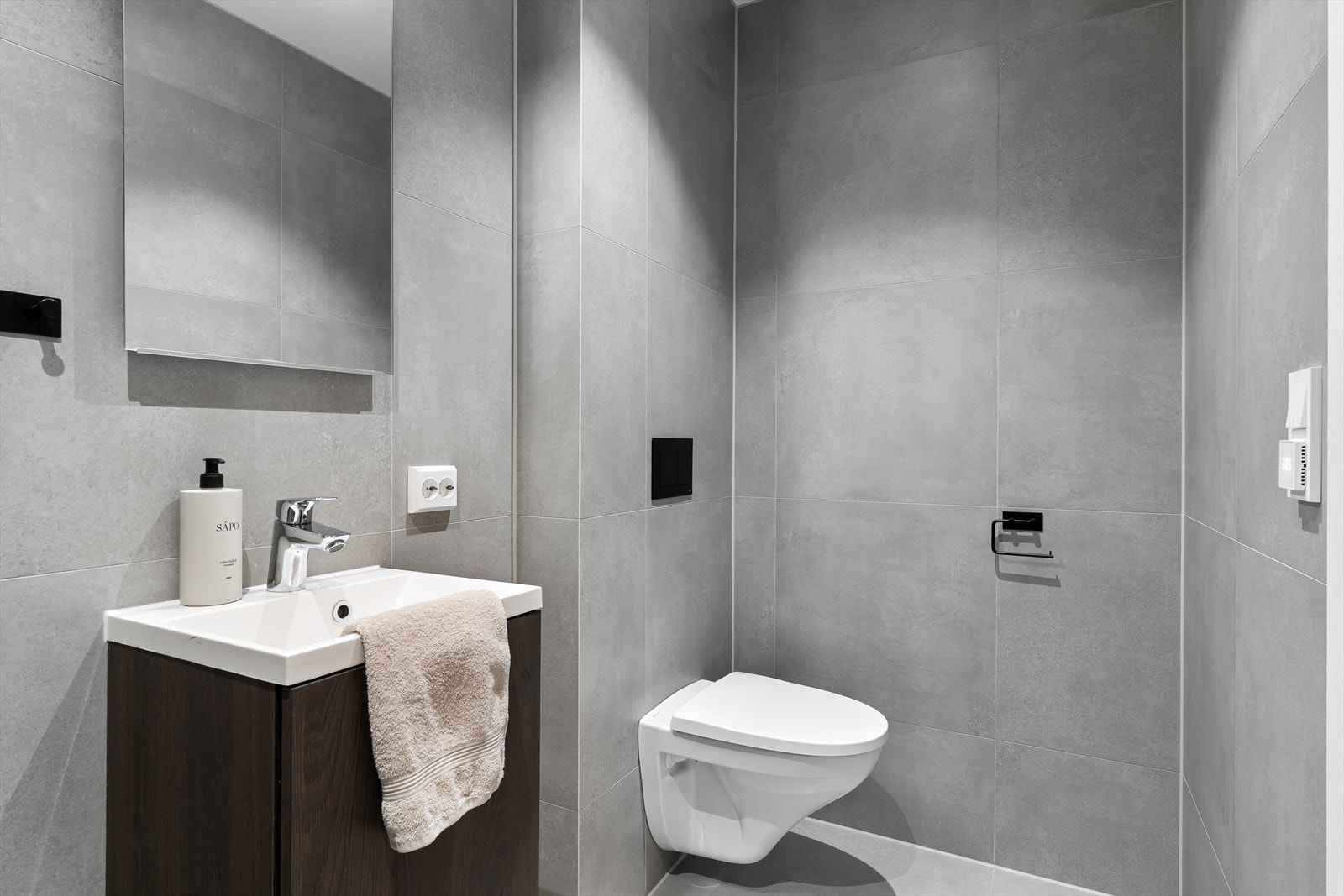 Bad nr. 1: Et innbydende, helfliset bad utstyrt med nedfelt servant, vegghengt toalett og praktiske dusjdører - en kombinasjon av stil og funksjonalitet Galleribilde