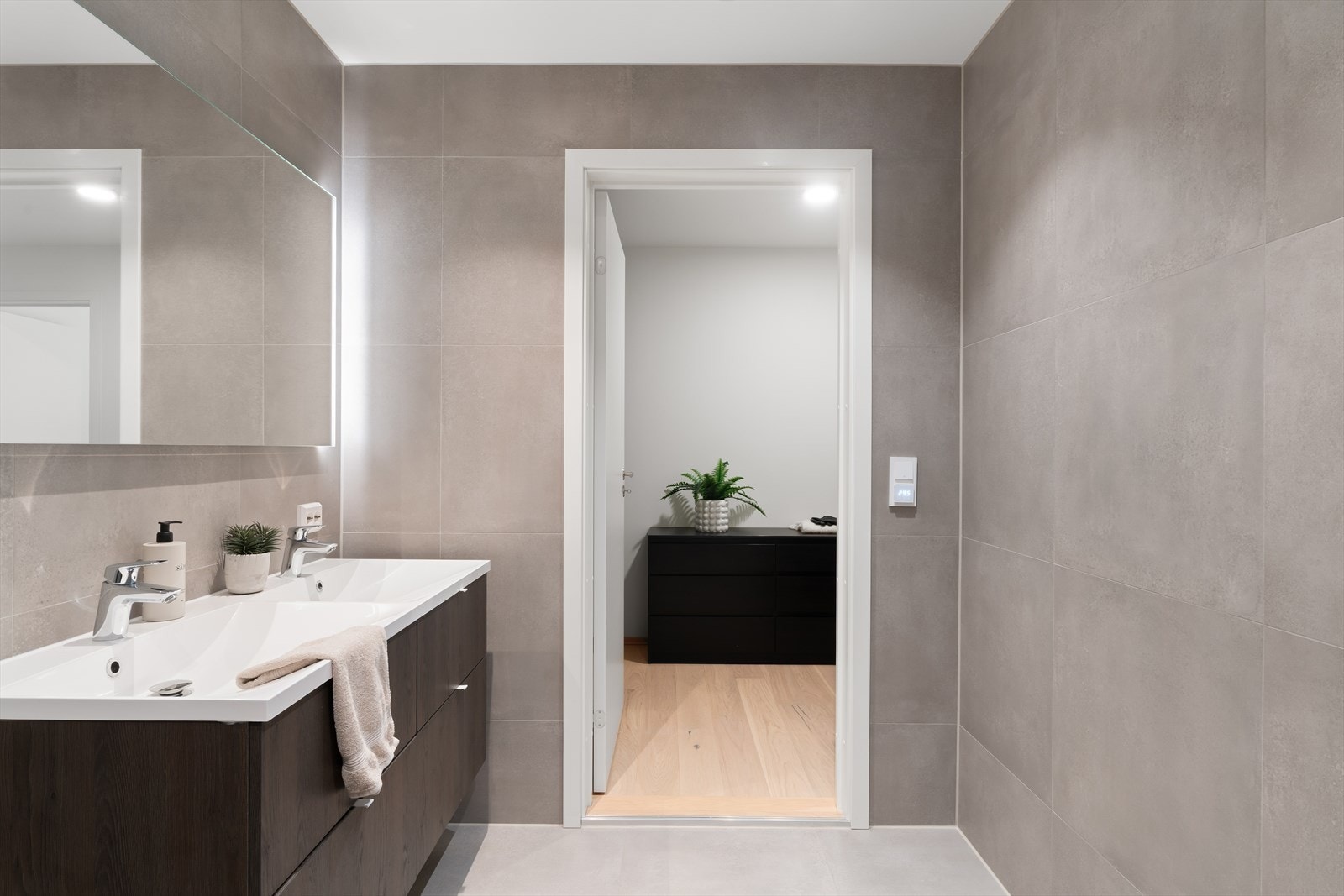 Bad nr. 2: Start og avslutt dagen kun et par skritt fra sengen! Et innbydende, helfliset bad med dobbel servant, vegghengt toalett og praktiske dusjdører Galleribilde