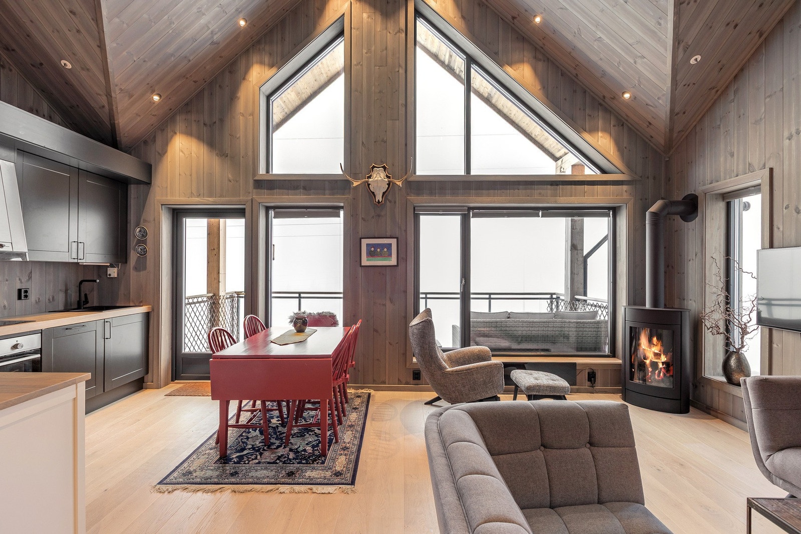 Den åpne himlingen og den gjennomgående bruken av trepanel gir rommet en lun og moderne fjellhyttefølelse. Galleribilde