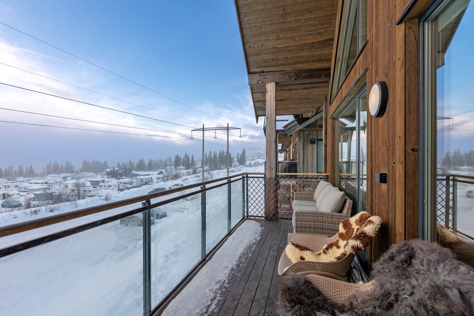 Balkong med terrassebord oppforet på betongdekke, med rekkverk i stål og glass samt topprekke i tre. Galleribilde