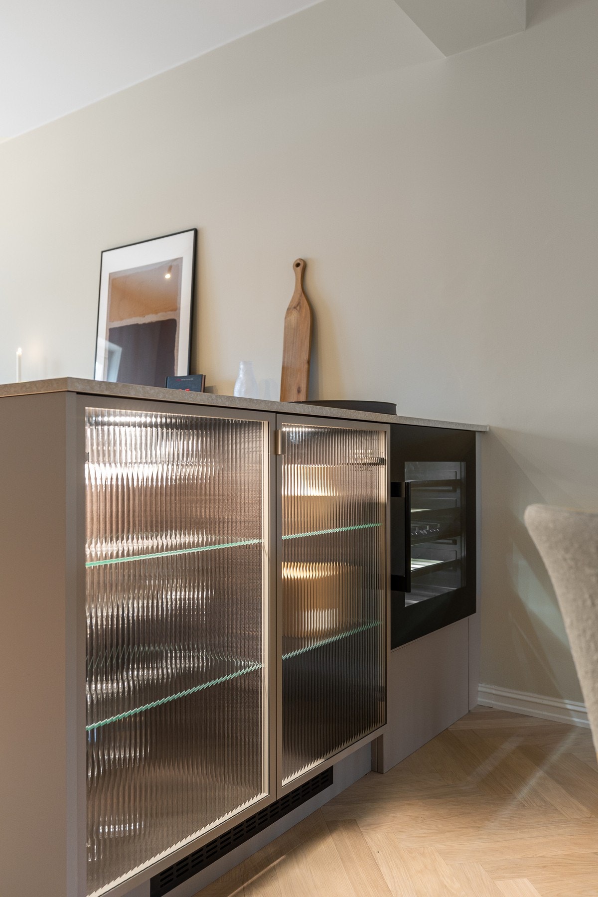 Designmessig utførelse med belysning og rillet glass. Luftig og åpen løsning mot stue og spisestue. Galleribilde