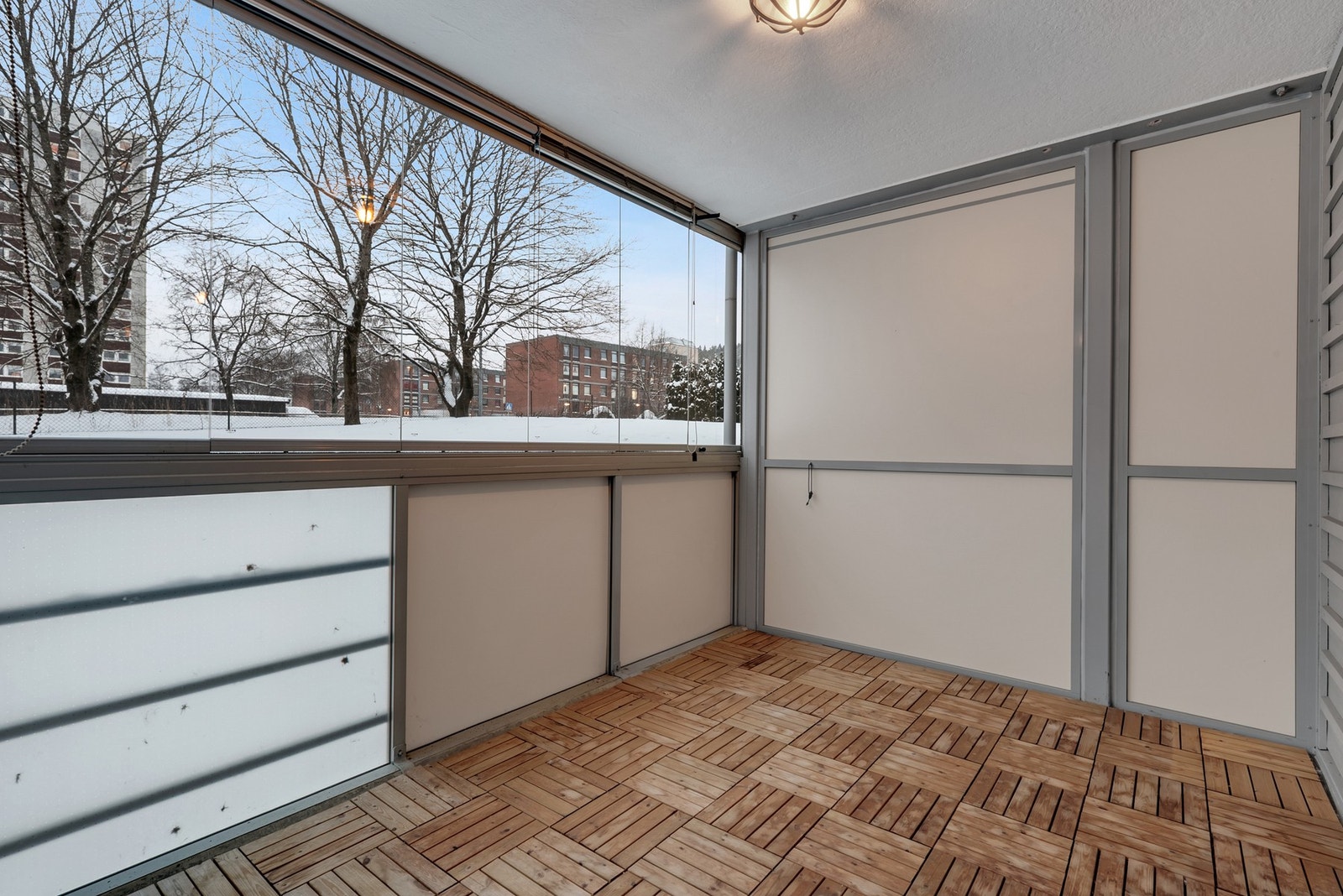 Den innglassede balkongen har terrassefliser i treverk som gir en lun og behagelig atmosfære. Galleribilde