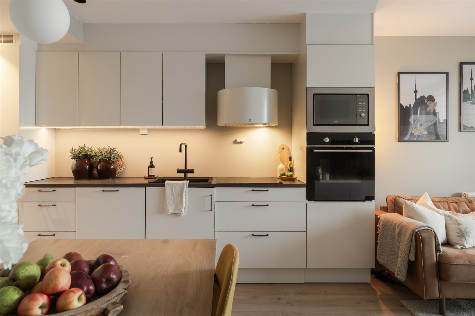 Pent HTH-kjøkken med slette fronter og integrerte hvitevarer som platetopp, stekeovn, mikrobølgeovn, oppvaskmaskin samt kombinert kjøl og fryseskap. Galleribilde