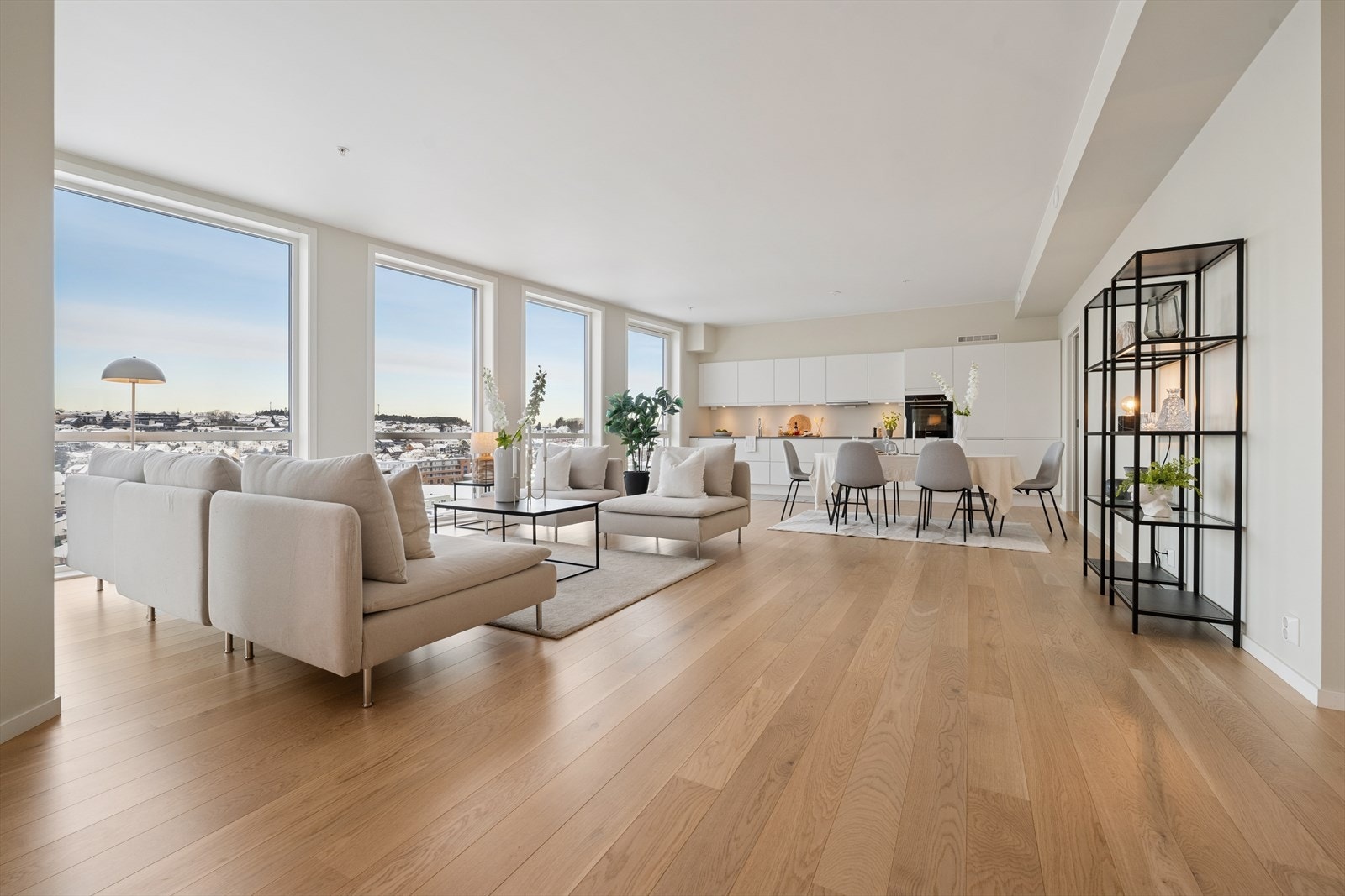 Lyst og romslig oppholdsrom med store vindusflater, åpen kjøkkenløsning og vakker utsikt som fyller rommet med naturlig lys. Galleribilde