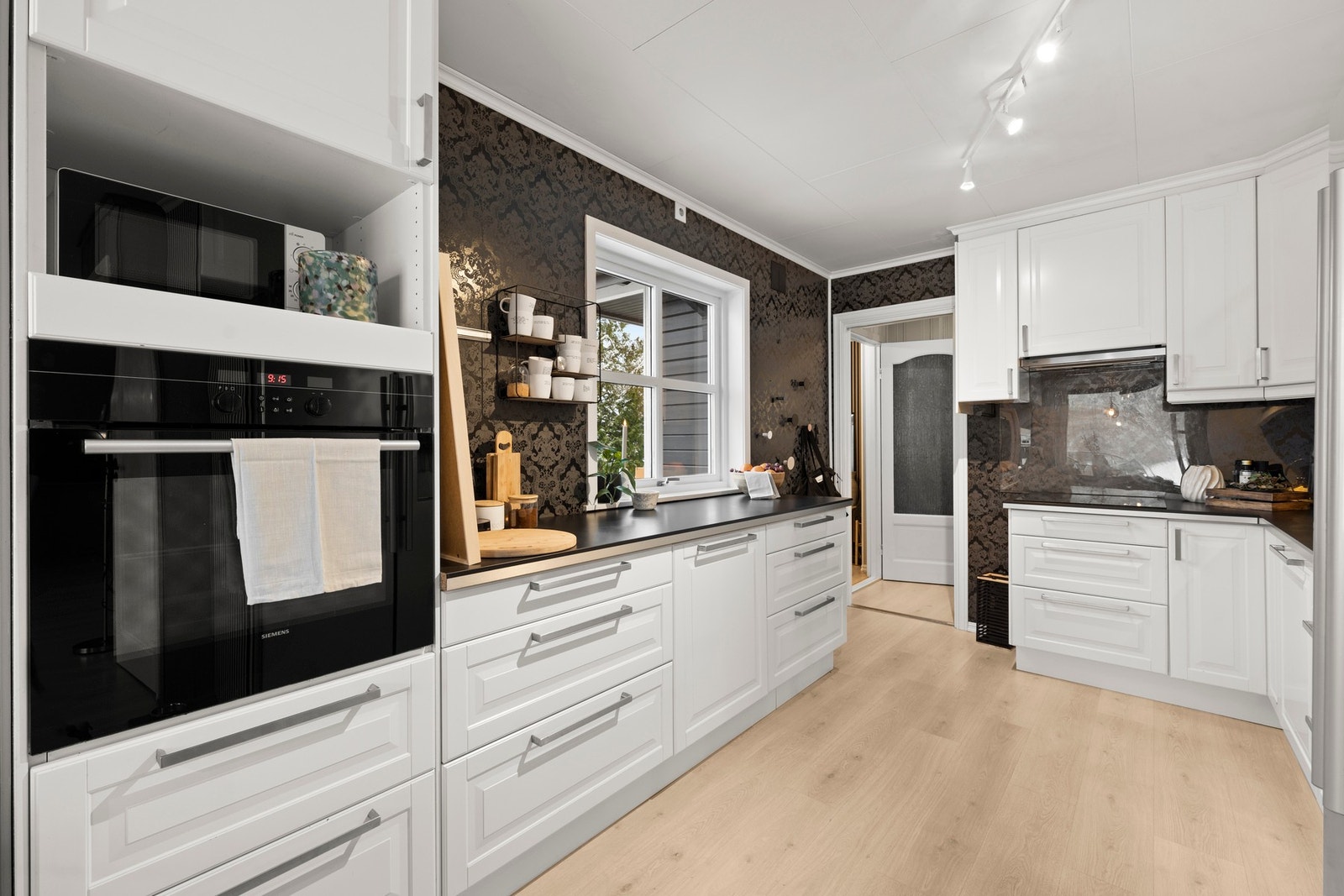 Innredningen fra Ikea er utført med profilerte fronter og benkeplate av laminat, og det er oppvaskmaskin, komfyr og induksjonstopp, samt opplegg for oppvaskmaskin. Galleribilde