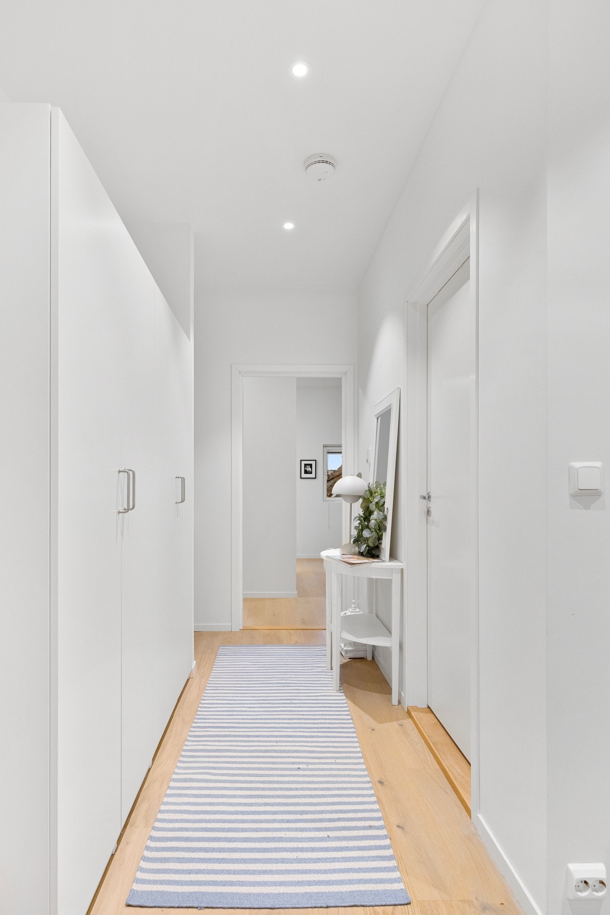 Lyst og moderne gangområde med hvite vegger og innfelte spotlights i taket. Galleribilde