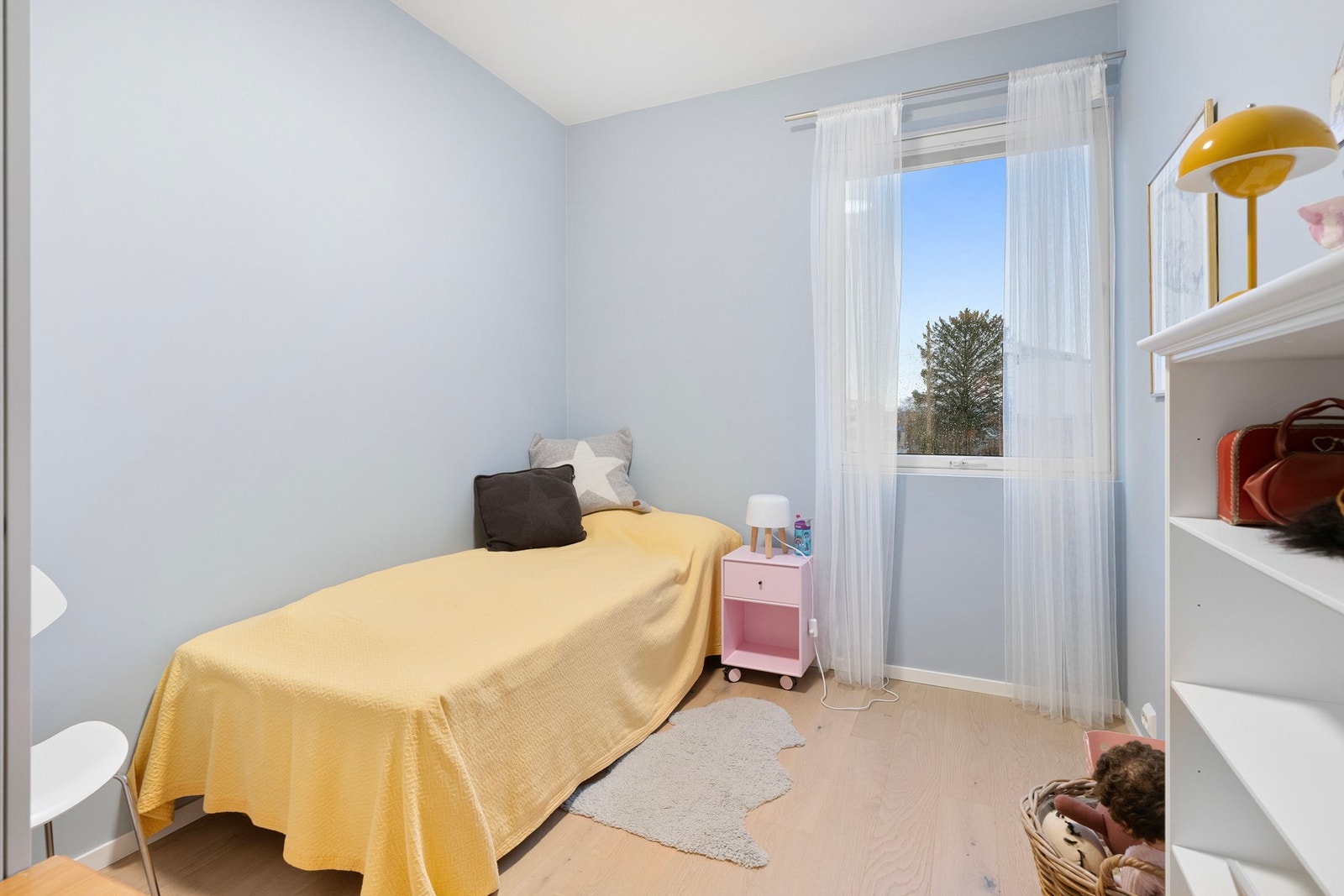 Soverom med lyseblå vegger og vindu som gir godt med naturlig lys. Galleribilde