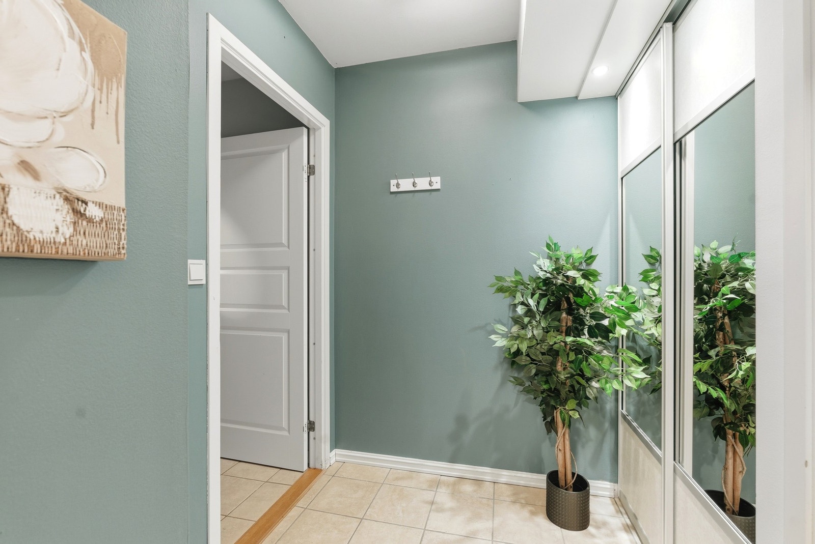 Innbydende entré/gang med lagringsplass i skyvedørsgarderobe. Fliser på gulv. Galleribilde