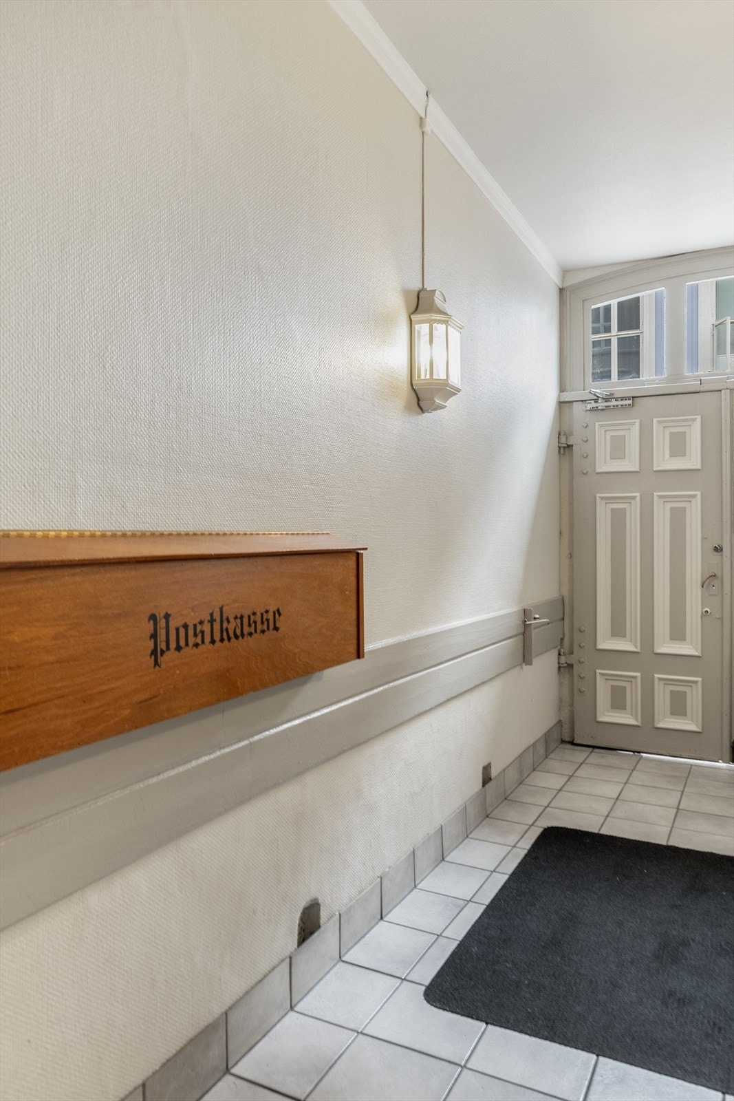 Adkomsten inn fra gateplan i et fint portrom med ærverdig eldre trapp som svinger seg opp i etasjene Galleribilde