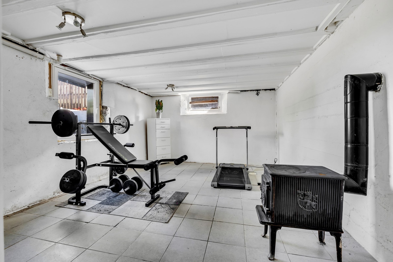 Treningsrom med flislagt gulv, malte murvegger og nytt vindu som tilfredsstiller krav til rømningsvei. Galleribilde