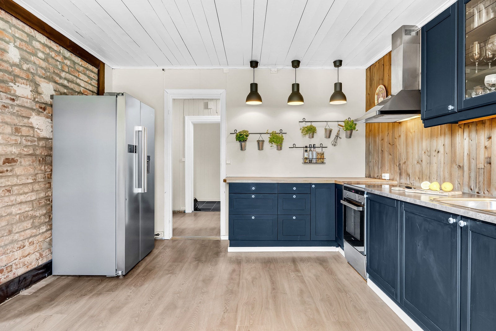 Veggene består av trepanel, malte panelplater og en mursteinsvegg mot stuen, som passer godt til boligens landlige stil. Galleribilde