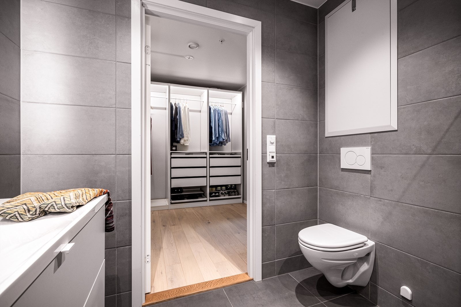 Badet tilhørende hovedsoverommet inneholder vegghengt toalett, helstøpt servant, skuffer under servant med slette fronter og dusjdører i klart glass. Galleribilde