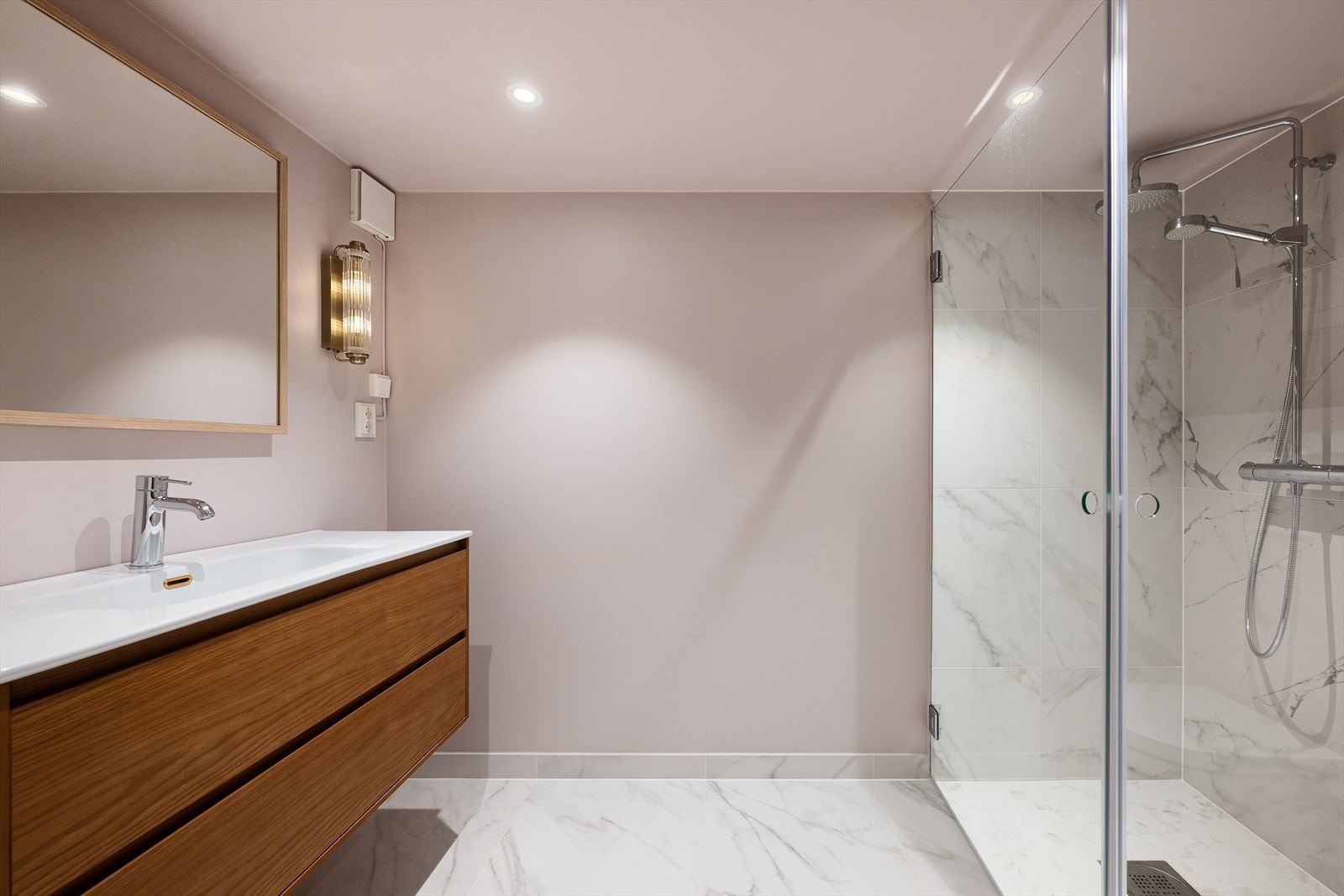 Badet har moderne fliseløsning med 60 × 60 cm fliser på veggene i dusjsonen, og gulvflisene er trukket ca. 9 cm opp på veggen som vannsikring på gulv. Det er varmekabler i gulvet som gir behagelig temperatur. Galleribilde