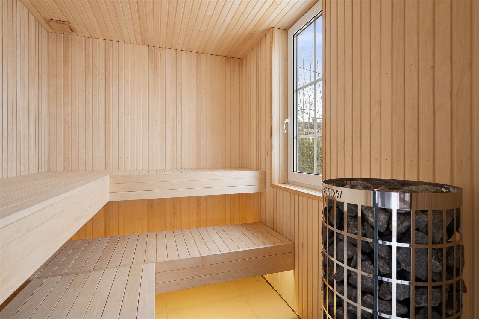 Badstuen har klassisk innredning med to benker, vindu mot bassenget og elektrisk badstueovn. Galleribilde