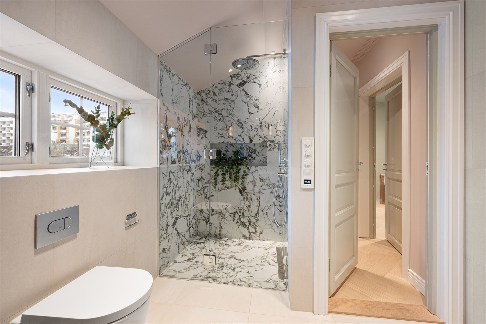 Videre er det vegghengt toalett samt dusjhjørne med fastmontert dusjvegg og dusjdør med hengsler. Dusjen er utstyrt med innfelt armatur, regnfallsdusj og hånddusj. Galleribilde