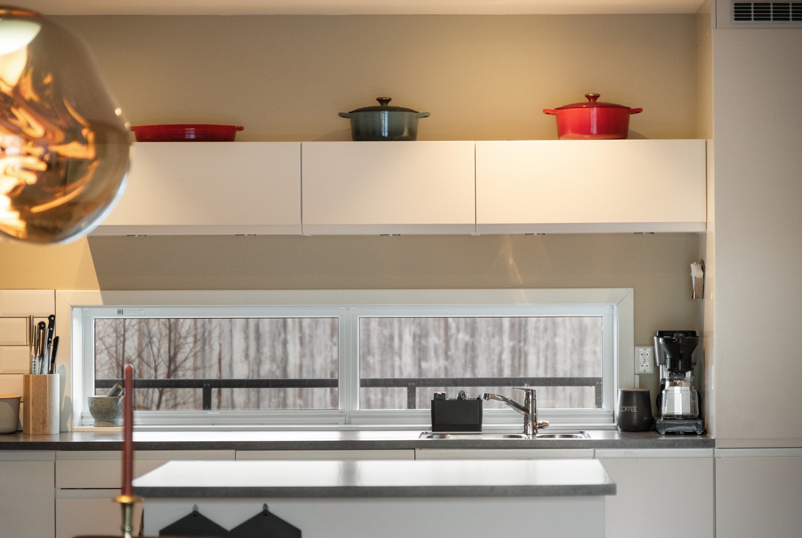 Vinduer over kjøkkenbenken åpner opp og skaper gjennomlysning i leiligheten. Galleribilde